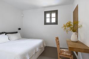 a bedroom with a bed and a table and a window at Acron Villas Paros in Kolympithres