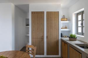 a kitchen with a wooden cabinet next to a table at Acron Villas Paros in Kolympithres