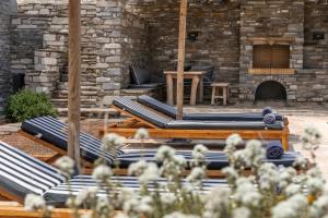 a group of lounge chairs in front of a stone building at Acron Villas Paros in Kolympithres