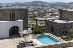 a villa with a swimming pool and two umbrellas at Acron Villas Paros in Kolympithres