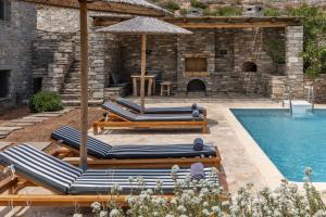 a group of lounge chairs and an umbrella next to a swimming pool at Acron Villas Paros in Kolympithres