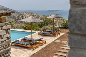 a group of lounge chairs and umbrellas next to a pool at Acron Villas Paros in Kolympithres