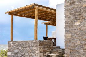 a stone wall with a wooden pergola at Acron Villas Paros in Kolympithres