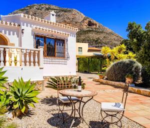 a house with a table and chairs and a mountain at Villa Llamedos Montgo Javea by Rock Rentals in Jávea