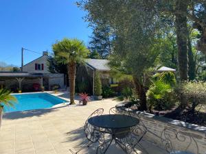 eine Terrasse mit Tisch und Stühlen neben einem Pool in der Unterkunft Gîte à la campagne in Malville