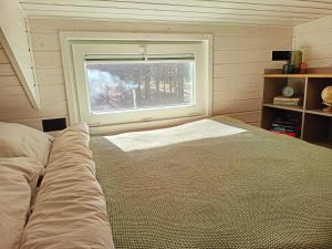 a bedroom with a large bed and a window at Tiny house in the forest in Szlachta