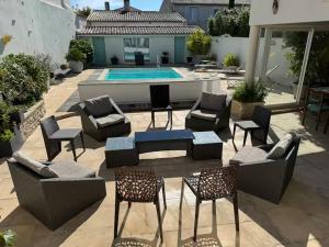 a patio with chairs and tables and a pool at ღ Ostaria - Maison Spacieuse, Piscine & Garage in La Couarde-sur-Mer