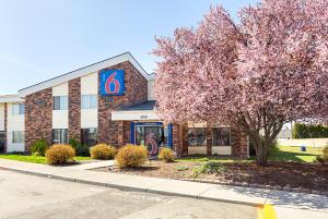 a building with a sign in front of a tree at Motel 6-Spokane, WA - East in Spokane Valley