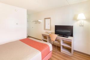 ein Hotelzimmer mit einem Bett und einem Schreibtisch mit einem TV in der Unterkunft Motel 6-Spokane, WA - East in Spokane Valley