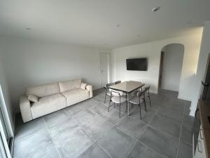 a living room with a couch and a table at La Maisonnette - Jardin & Calme in Saint-Ouen-des-Alleux