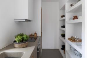a kitchen with white walls and a sink and shelves at Acron Villas Paros in Kolympithres