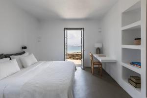 a bedroom with a bed and a desk and a window at Acron Villas Paros in Kolympithres