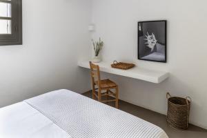 a bedroom with a bed and a table and a chair at Acron Villas Paros in Kolympithres