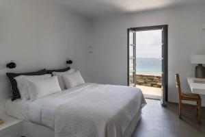 a white bedroom with a bed and a view of the ocean at Acron Villas Paros in Kolympithres