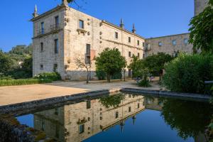 an old building with a reflection in a pool of water at Pousada Mosteiro Amares in Bouro
