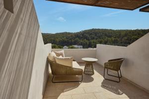 a balcony with chairs and a table and a view at Cala San Miguel Ibiza Resort, Adults only, Curio Collection by Hilton in Puerto de San Miguel