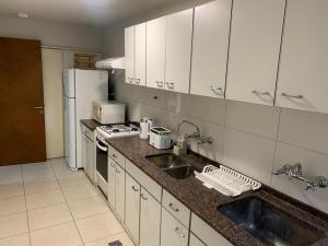 a kitchen with white cabinets and a sink and a refrigerator at Microcentro Mendoza in Mendoza +2 photos