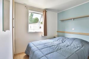 a bedroom with a blue bed and a window at Camping maeva Club L'Atlantique in Angles +68 photos