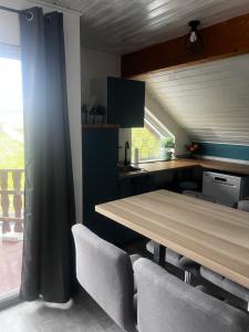 a kitchen with a wooden table and some chairs at Modern attic apartment with pool view AC and gym in Hütschenhausen