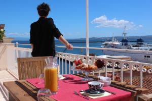 una persona in piedi su un balcone con tavolo e drink di Nichotel a Carloforte