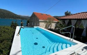a swimming pool in front of a house next to a lake at Villa Soldo by Villas Guide in Hodilje