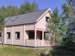 a large white house with a gambrel roof at Domki w brzozach in Brajniki