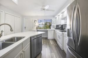 a kitchen with white cabinets and a stainless steel refrigerator at Loggerhead 282 condo in Sanibel
