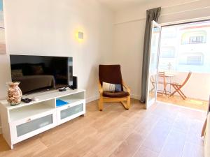 Una sala de estar con un televisor y una silla. en Apartamento 2M - Praia do Carvoeiro, en Carvoeiro