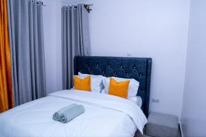 a bed with a blue headboard and orange pillows at Quiet a Gem off Thika Highway in Ruiru