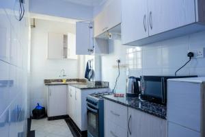 a kitchen with white cabinets and a black stove top oven at Quiet a Gem off Thika Highway in Ruiru