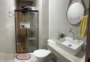 a bathroom with a toilet and a sink and a mirror at Casa temporada in Camaçari