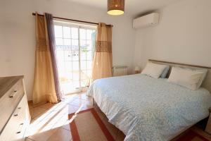 ein Schlafzimmer mit einem Bett und einem großen Fenster in der Unterkunft Casa Bonita in Lagoa + 50 Fotos