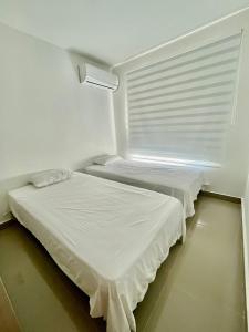 two beds in a white room with a window at APARTAMENTO al NORTE DE VALLEDUPAR in Valledupar