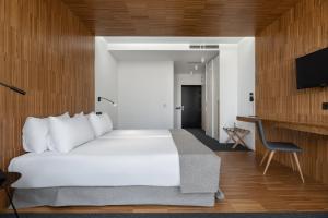 a bedroom with a white bed and a flat screen tv at Pousada Ribadumia in Ribadumia