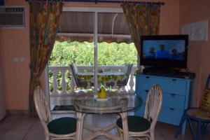 a dining room with a glass table with chairs and a television at Sun Caraibes in Orient Bay