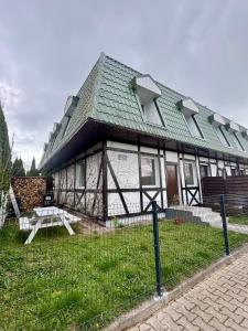 a house with a green roof with a bench in front of it at Corner House Plesna in Pleśna