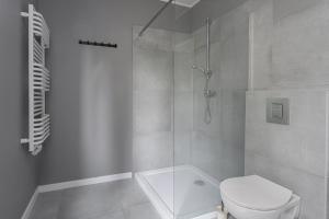 a white bathroom with a shower and a toilet at Apartament Pomarańczowy Gdańsk 80 metrów z widokiem na ogród in Gdańsk