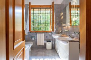 une salle de bain avec deux lavabos et un WC et une fenêtre dans l'établissement Villa Punta Sasso, à Manerba del Garda 28 autres photos