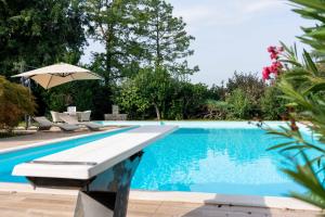 - une piscine avec un parasol et des chaises à côté dans l'établissement Villa Punta Sasso, à Manerba del Garda