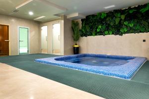 a swimming pool in a room with a plant on the wall at Mardan Hotel in Shymkent