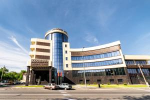 a large building with cars parked in front of it at Mardan Hotel in Shymkent