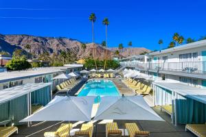 パーム・スプリングスにあるThe Skylark, a Palm Springs Hotelのラウンジチェアとパラソル付きのスイミングプール