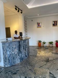 Un hombre sentado en un mostrador en un vestíbulo. en Tofana Hotel and Suites, en Mama
