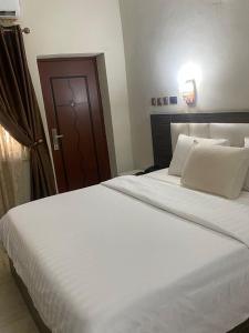 1 dormitorio con 1 cama blanca grande y puerta marrón en Tofana Hotel and Suites, en Mama
