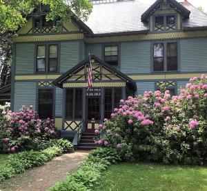 a blue house with pink flowers in front of it at Amherst Inn in Amherst