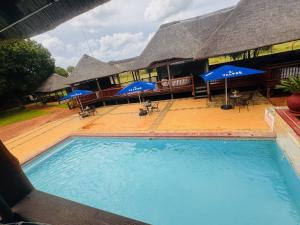 a large swimming pool in front of a building with umbrellas at Falcon Lodge Bela in Bela-Bela