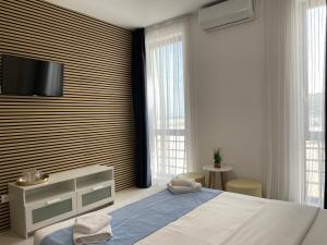 a bedroom with a bed and a tv on a wall at Beach Rooms Roberta in Mamaia