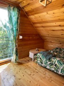 a bedroom with a bed and a window in a log cabin at Domki w brzozach in Brajniki