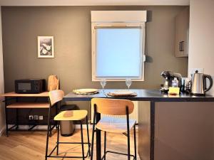 Una cocina con un mostrador con sillas y una ventana. en Le BraSeo, nice studio with parking in Rennes, en Rennes