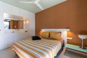 ein Schlafzimmer mit einem Bett mit gestreifter Decke und einem Spiegel in der Unterkunft Casa Nera in Pianottoli-Caldarello + 29 Fotos